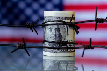 Conceptual image: barbed wire against US Dollar bancnotes as symbol of economic warfare, sanctions...