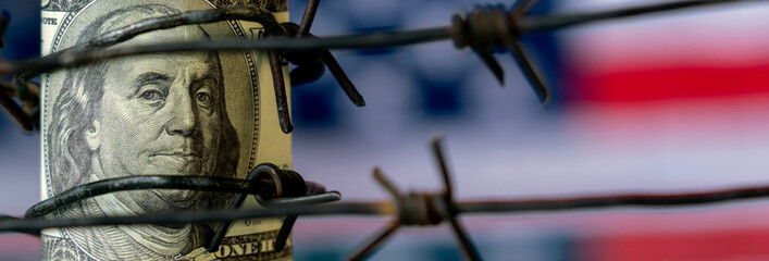 Conceptual image: barbed wire against US Dollar bill as symbol of economic warfare, sanctions and...