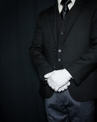 Portrait of Butler or Servant in Dark Suit and White Gloves Standing at Formal Attention. Concept...