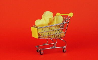 Potato chips in a shopping cart on a red background