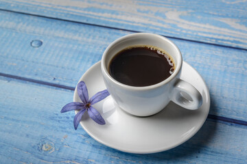 Coffee. White cup of coffee on a blue wooden table.