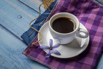 Coffee. White cup of coffee on a blue wooden table.