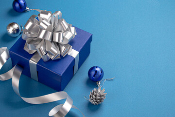 Christmas present box wrapped in blue paper with silver ribbon and bow, Christmas round balls...