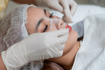 Fototapeta na wymiar Close up the dermatologist apply the facial remover for preparing the skin for the facial treatment