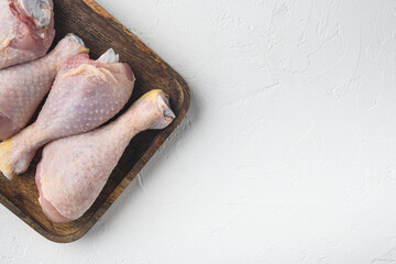 Uncooked Chicken Thigh or legs, drumsticks, on wooden tray, on white stone  background, top view flat lay, with copy space for text