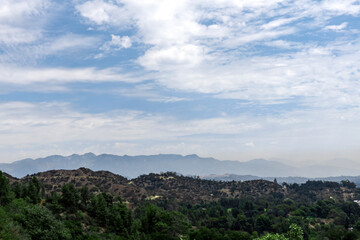 Hills or mountains covered with trees in Los Angeles area with silhouettes in the background
