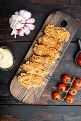 Spicy deep fried breaded chicken wings on dark wooden background, top view