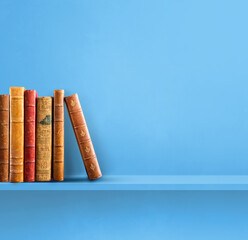 Row of old books on blue shelf. Square background