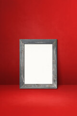 Wooden picture frame leaning on a red wall