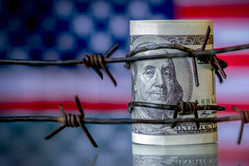 Barbed wire against US Dollar bancnotes as symbol of economic warfare, sanctions and embargo...