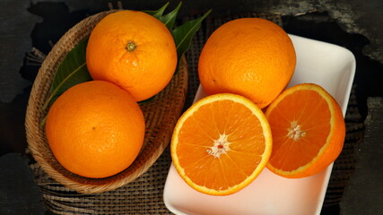 Fresh orange fruits in a basket with a white plate