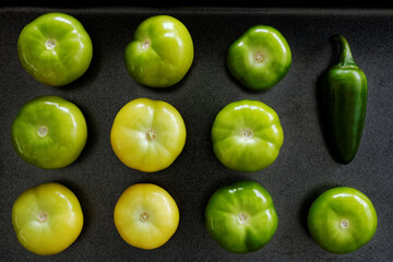 Tomatillos with one jalapeno on baking tray. Home cooking.
