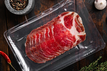 Sliced Ham Salami coppa plastic pack, on old dark  wooden table background, top view flat lay