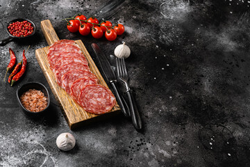 Fototapeta premium Traditional dry cured Milano salami, on black dark stone table background, with copy space for text