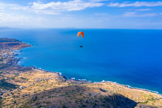 Paraglider flying over Milatos village, Crete, Greece.