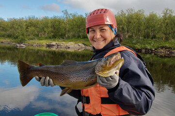 Fisherwoman caught a large salmon in the northern river. Kola Peninsula, Russia.