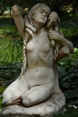 Fototapeta na wymiar sculpture of a woman with a sheep or goat in her arms, in the botanical garden of buenos aires