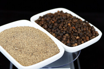 granulated and ground black pepper standing side by side,close-up of black pepper in plate,