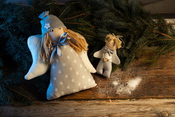 Festive decoration for Christmas. Plush Angels on old boards and spruce branches.
