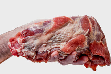 A hand holds a large piece of raw pork, isolated on a white background