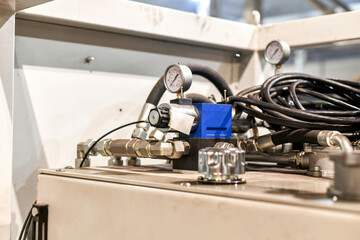 Hoses connected to the hydraulic oil station on which there is a pressure gauge in the workshop.