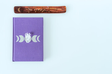 Flat lay of moon journal with angel quartz crystal and burning incense on white background with copy space
