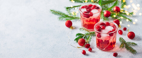 Alcoholic cocktail or non-alcoholic mocktail with vodka and iced cranberries with fir branches and glowing garland for christmas
