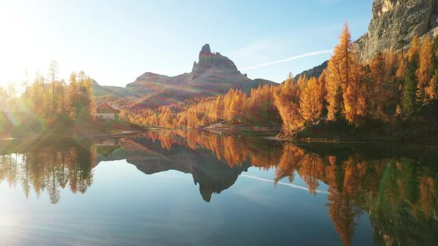 Drone flyght over Federa Lake in sunrise time. Autumn mountains landscape with Lago di Federa and bright orange larches in the Dolomite Apls, Cortina D'Ampezzo, South Tyrol, Dolomites, Italy