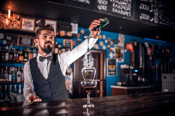 Barman mixes a cocktail behind the bar