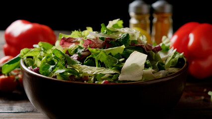 Mix of fresh green salad in a plate on the table with vegetables and spices.