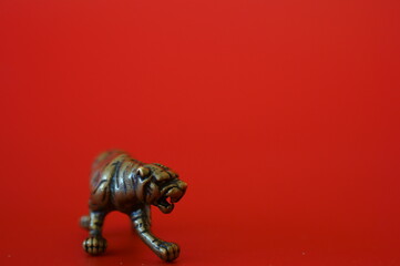 Metal tiger figurine on a red background. Close-up subjects.