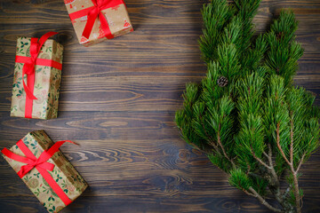 Christmas gift boxes .on wooden background with Christmas tree branch. Xmas and Happy New Year theme. Flat lay, top view. Copy space.