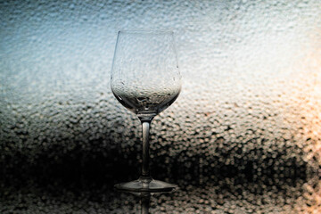 Transparent wine glass on the background of drops on the glass, shiny bokeh. A wine glass on the background of blurred drops. Wine glass shot in close-up