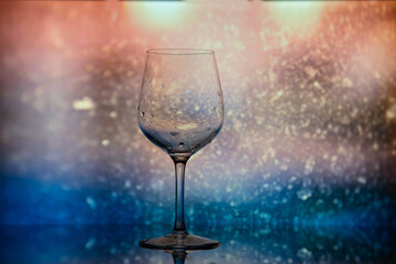 Transparent wine glass against the background of dust on the glass, shiny bokeh. A wine glass against a background of blurred dust particles. Wine glass shot in close-up