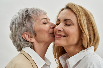 Older Caucasian mother kiss adult daughter