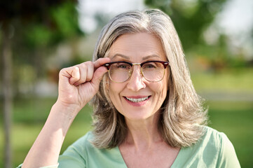 Woman touching glasses looking at camera
