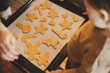 Cute little daughter and mother holding tray with christmas cookies close up in modern kitchen....
