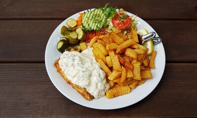 French fries with shrimps in white sauce and salad on a white plate