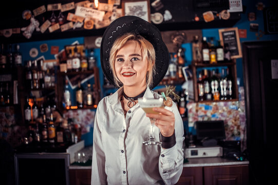 Confident woman barman adds ingredients to a cocktail in pub