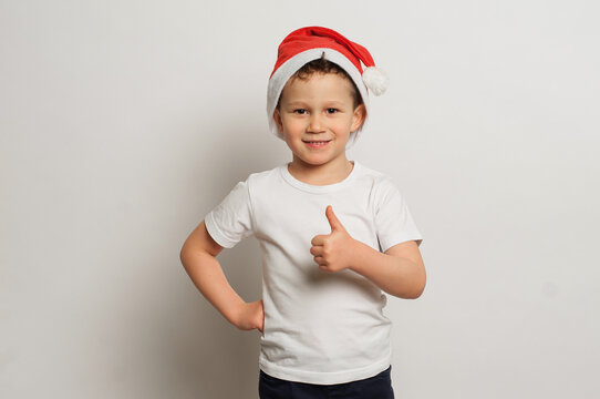 boy 7-9 years old in santa claus hat rejoices, new year mood, holiday concept