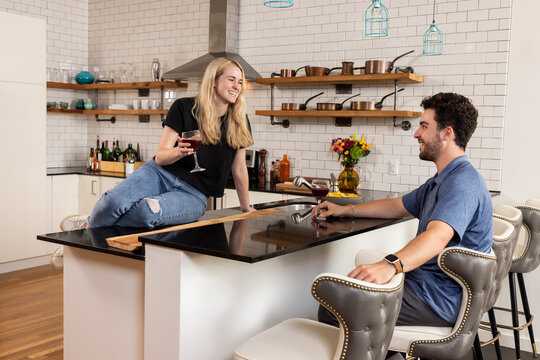 Couple on first date having a glass of wine in kitchen. 