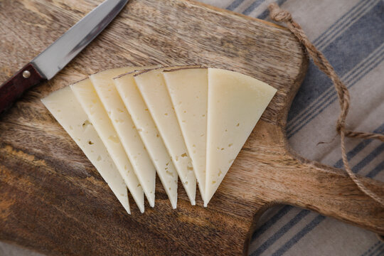 Slices of spanish manchego cheese on a wooden background