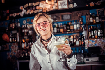 Charismatic woman bartender places the finishing touches on a drink at bar
