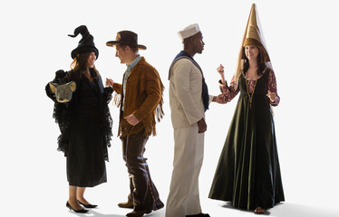 Group of four friends all dressed in Halloween costumes dancing and parting together against a white background