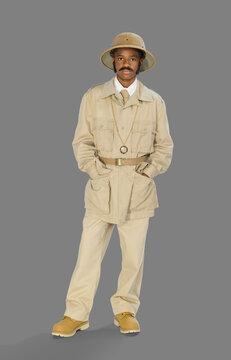 Full length portrait of a boy dressed up as archaeologist mummy hunter for Halloween, against a gray background