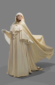 Woman dressed as a ghost in Halloween costume gliding and hovering in frame against gray background