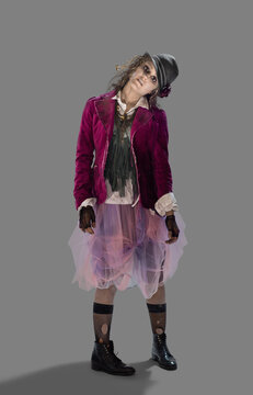 Portrait of a zombie woman looking into camera with a crooked neck and mindless expression, against gray background