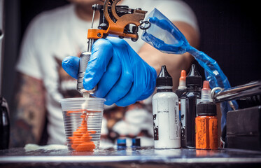 Hand of a tattoo specialist with a tattoo machine.