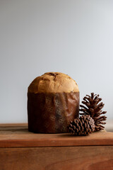 delicious panettone on a wooden table, with pine cones on the side, christmas day