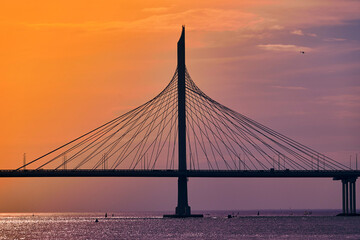 Cable-stayed bridge over the river at sunset. Water landscape.